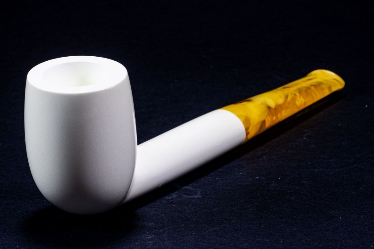 Classic Meerschaum Liverpool pipe featuring a minimalist white bowl and sleek amber stem, displayed on a black surface